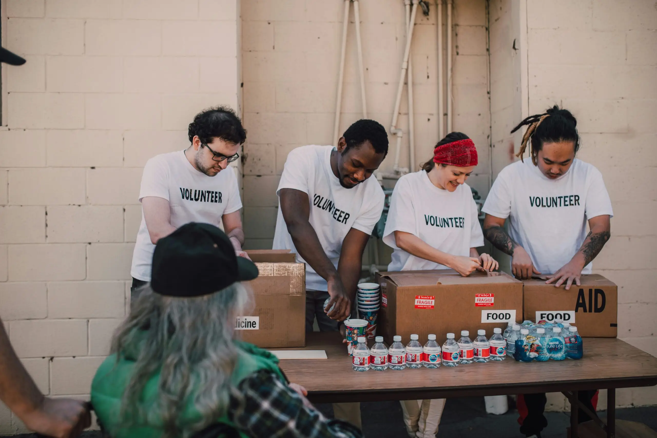 Group of volunteers organizing and distributing aid packages and bottled water outdoors.
