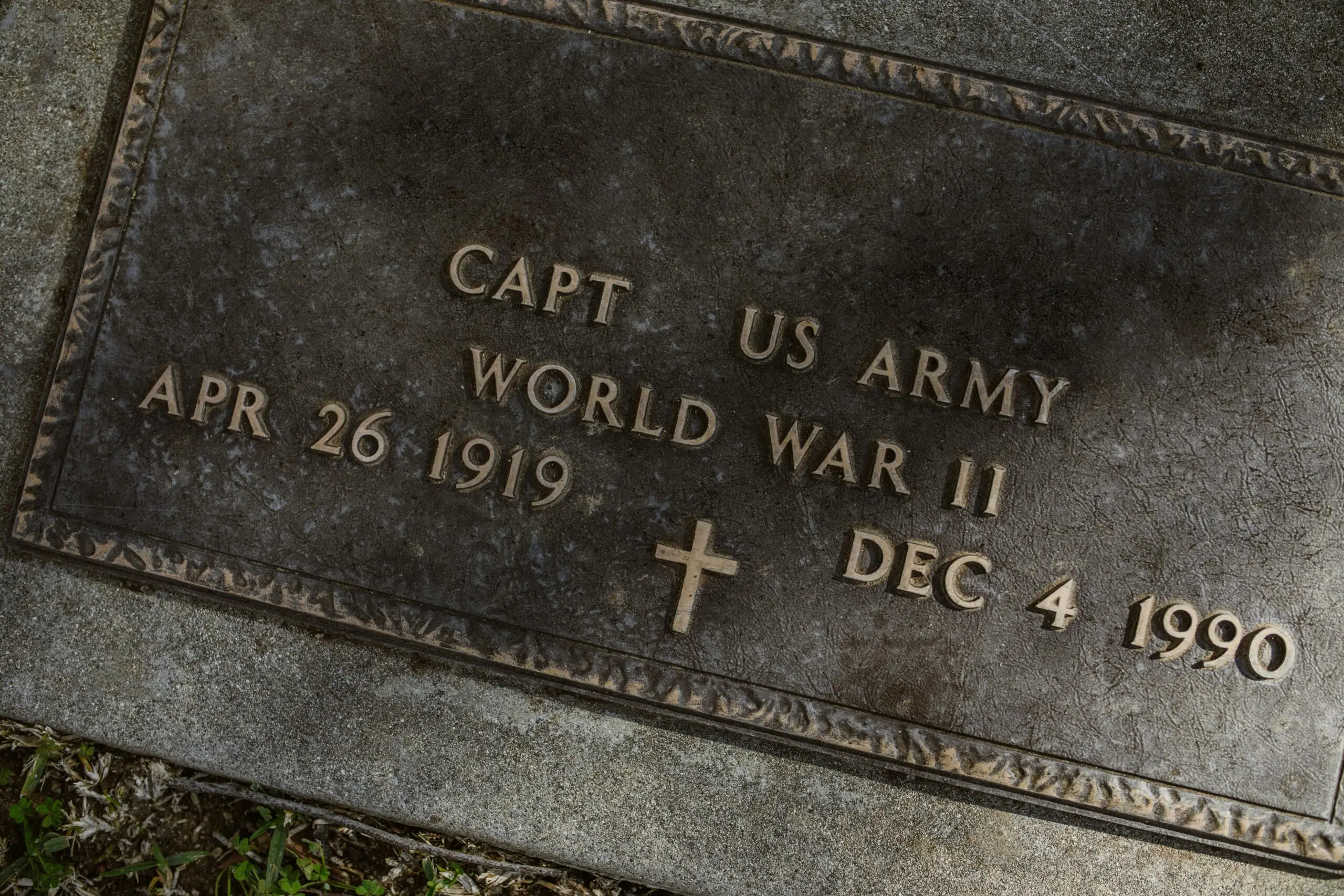 A close-up of a World War II US Army captain's gravestone with detailed inscription.