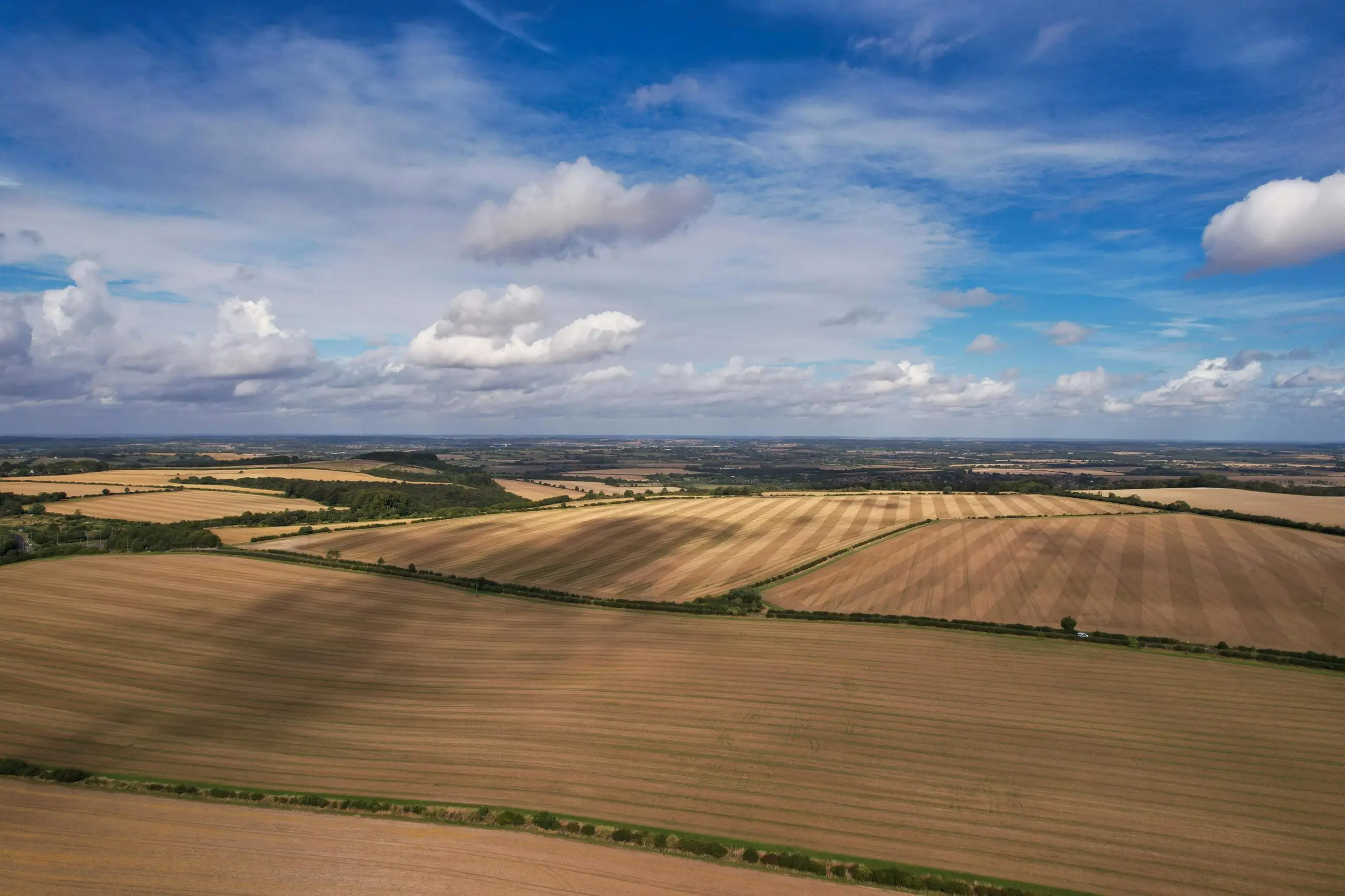 Expansive aerial landscape of fields in Central Bedfordshire, England, under a blue sky.
