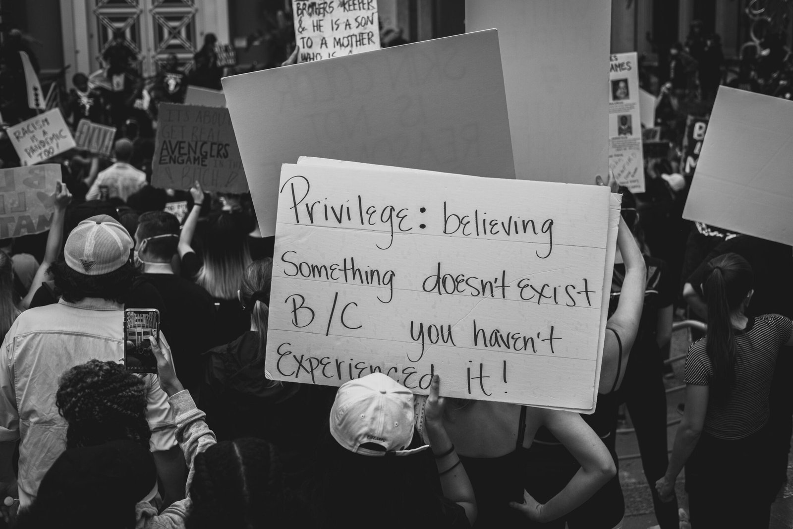 Monochrome image capturing a social justice protest with messages on placards.