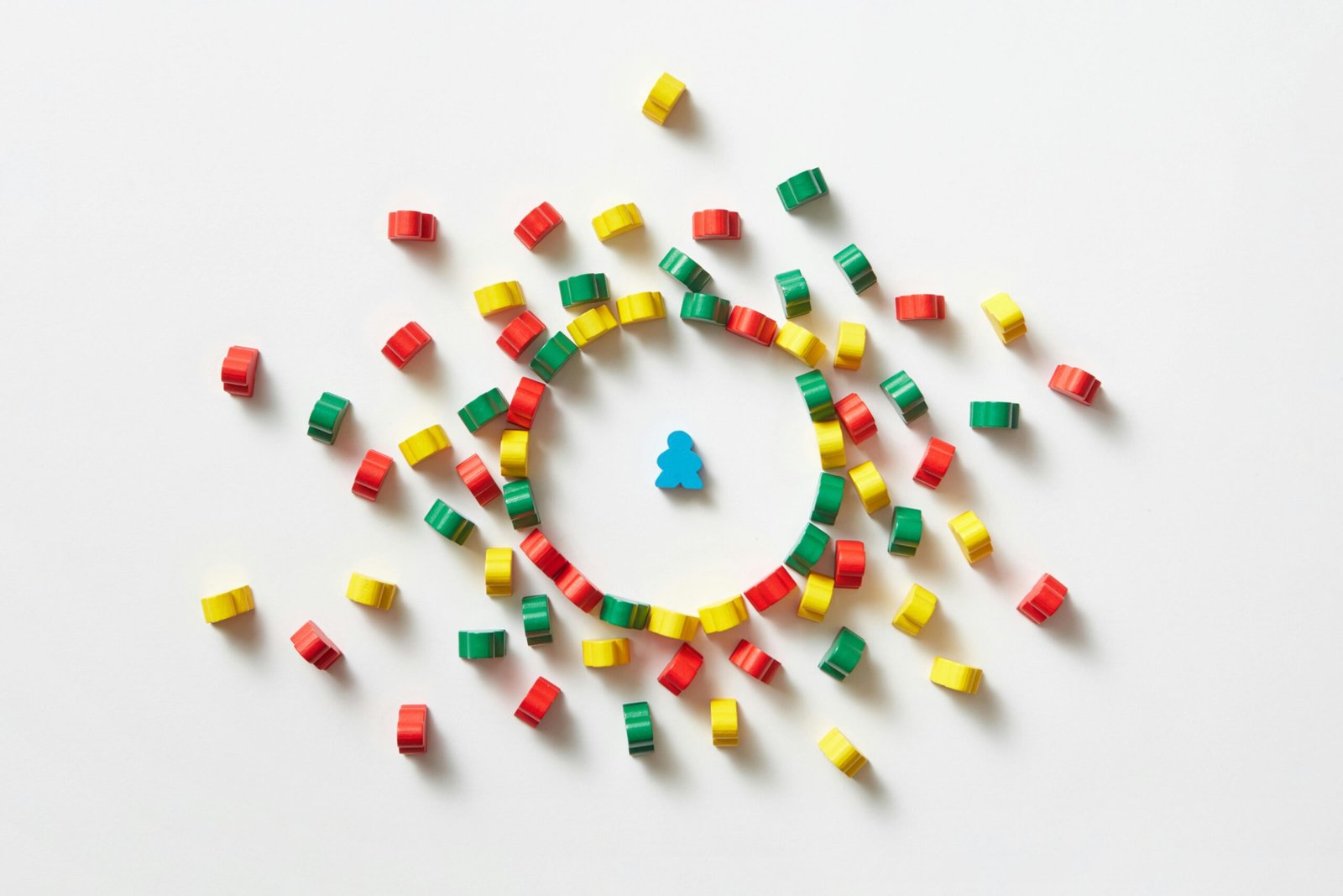 Abstract composition featuring a single blue pawn surrounded by colorful circular pieces on a white background.